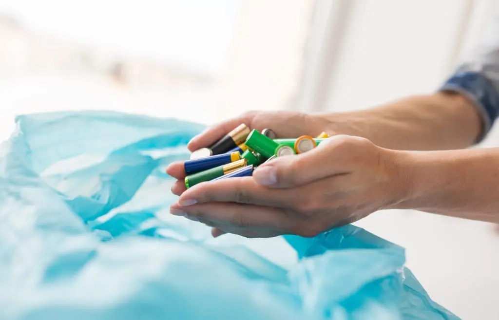 Image of person putting used batteries into plastic bag for recycling