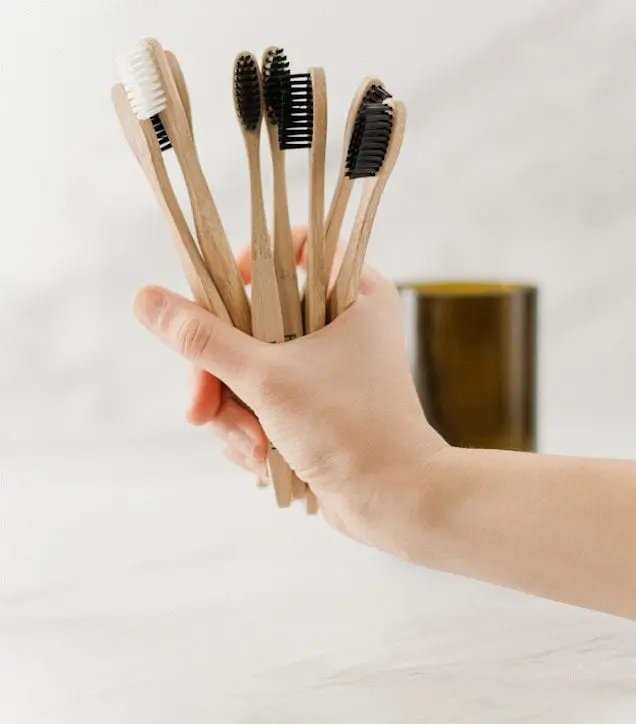 Image of woman's hand holding a selection of wooden toothbrushes