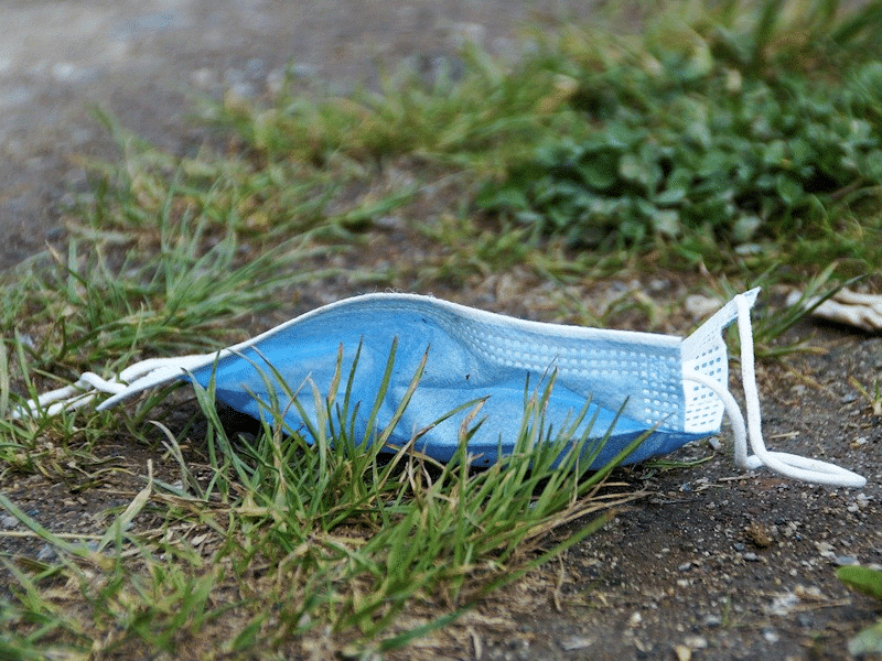 Discarded single use face mask lying on grass