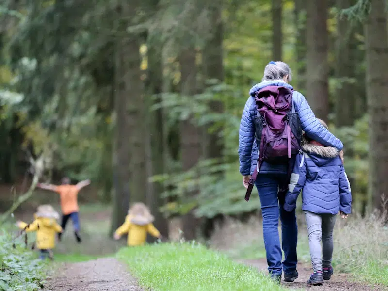 Woman and children walking in woodland.