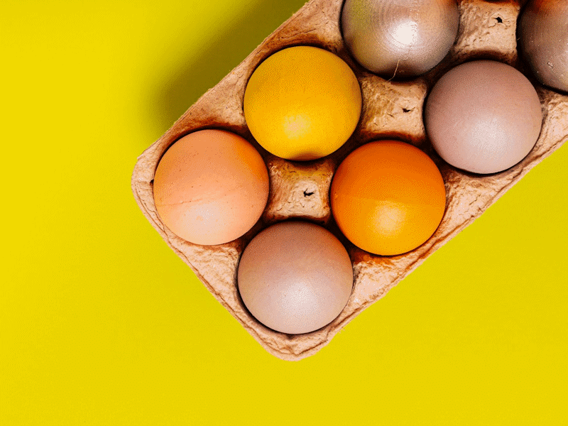 Box of eggs on bright yellow background.