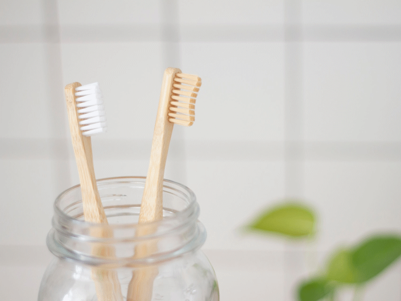 Two bamboo toothbrushes in a glass jar.