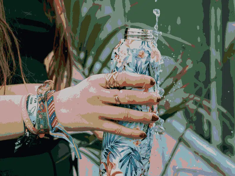 Girl holding reusable bottle under tap.