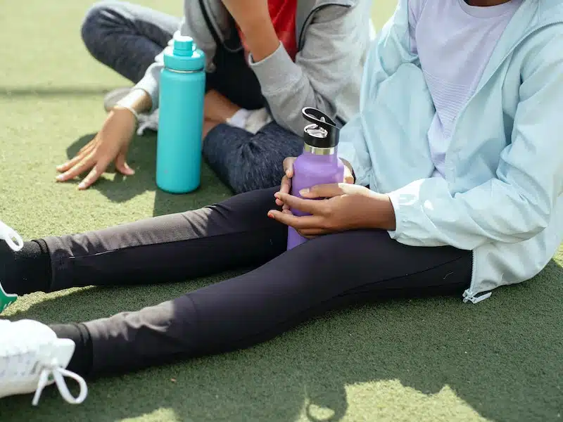 Two women sitting with reusable drinks bottles.