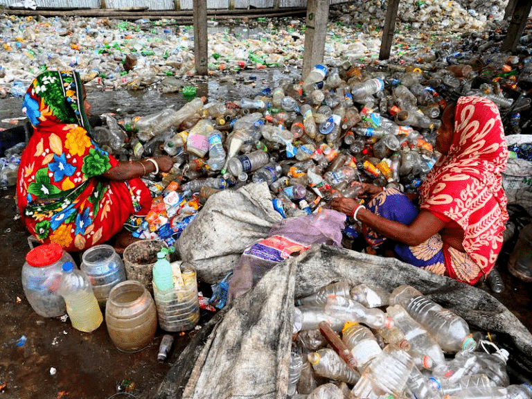 Women divide waste plastic into separate heaps.