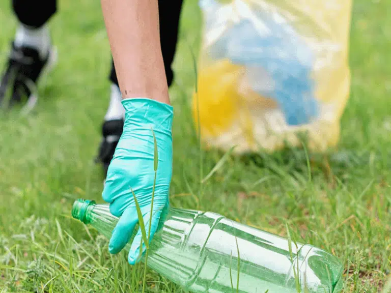 Person picking up a plastic drinks bottle as part of a litter pick.