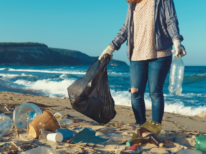 Woman picking up plastic waste on a beach